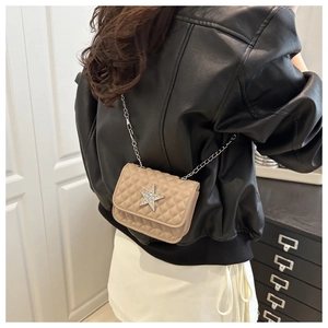 Detail of diamond star quilted crossbody bag with silver chain strap on a model