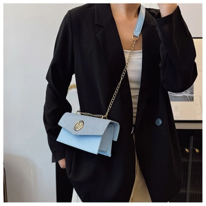 Dettaglio della piccola borsa quadrata azzurra con logo M dorato e tracolla a catena