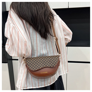Detail of brown leather saddle bag with geometric pattern flap and adjustable strap