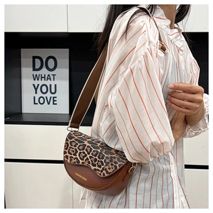Detail of leopard print saddle bag featuring gold FASHION & BAGS lettering and wide strap
