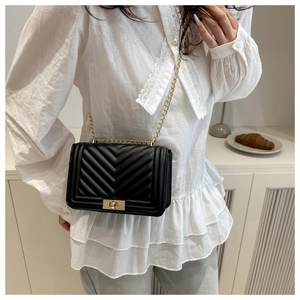 Detail of black V-quilted leather crossbody bag with golden rectangular clasp and chain strap