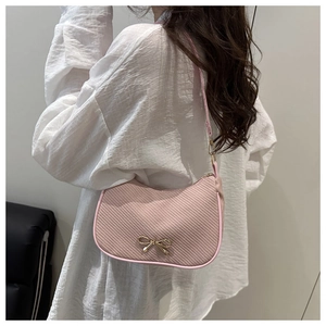 Detail of pink twill fabric hobo bag featuring a golden bow metal buckle and shoulder strap