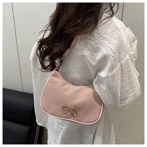 Detailed close-up of a pink bow shoulder bag with textured woven fabric and gold hardware