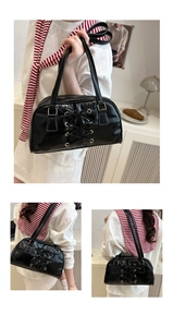 Detailed view of black patent leather hobo bag with unique front lace-up design and metal eyelets
