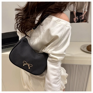 Detail of black leather hobo bag featuring a gold bow buckle and French style aesthetic