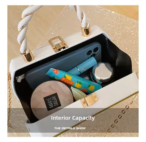 Macro shot of internal capacity of a white box bag with golden clasp and woven handle