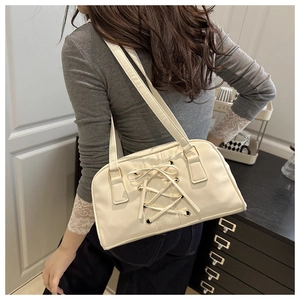 Close-up of cream white retro shoulder bag featuring lace-up details and golden eyelets