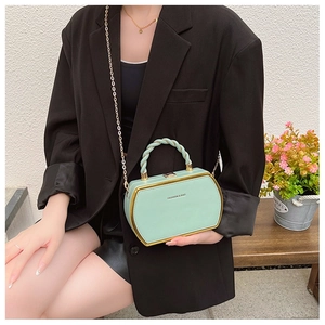 Detail of mint green box bag with gold metal trim and twisted handle on a model