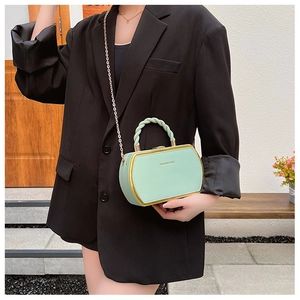 Detail of mint green box bag with gold metal frame and stylish twisted handle