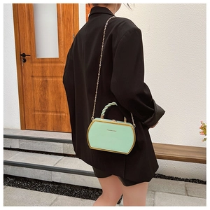 Detail of mint green mini box bag with gold metal frame and twisted top handle strap