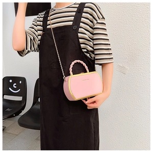 Detail view of pink mini crossbody bag with braided rope handle and gold metal frame