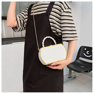 Detail of white box bag with gold metal frame, twisted handle, and chain strap