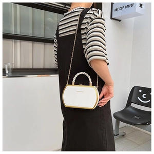 Fashionable white crossbody box bag with gold trim and chain strap shown on a model