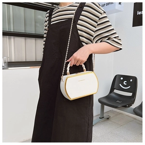 Detailed shot of white box bag with gold metal trim and stylish woven handle on a model