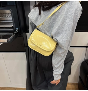 Lifestyle view of the bright yellow glossy crossbody bag with flap and round buckle