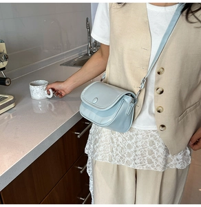 Detail of light blue crossbody bag with smooth PU finish and magnetic flap closure