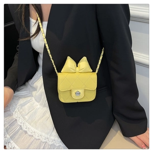 Detail of yellow quilted crossbody bag with bow decoration and silver floral clasp