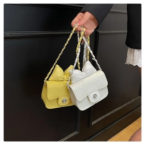 Detail of woven mini crossbody bags with bow accent and flower-shaped metal clasp