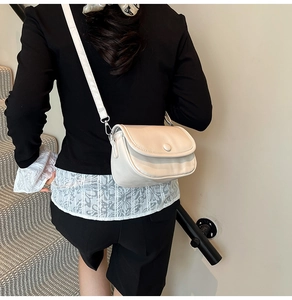 Minimalist beige crossbody bag styled on shoulder with soft leather and flap closure