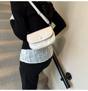 Macro detail of the creamy white PU leather texture and round button on a small square bag