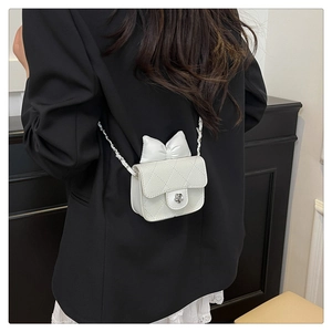 White quilted mini crossbody bag with leather bow and flower lock on model shoulder