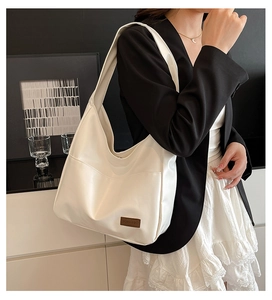 Detail of white matte leather hobo bag with vintage brown brand label on the front