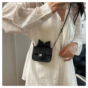 Detail of a quilted mini crossbody bag with a black bow and camellia metal lock buckle