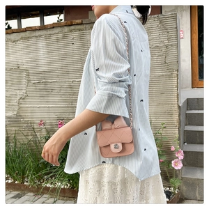 Outdoor shot of light pink quilted crossbody bag with bow and chain strap on a model