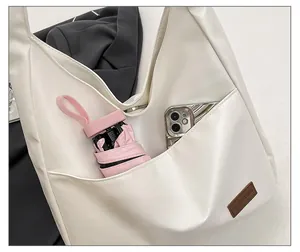 Detail showing front pocket of white PU tote bag holding phone and umbrella