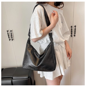 Dettaglio della borsa hobo nera in pelle martellata con forma a mezzaluna e tracolla larga