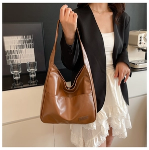 Detailed close-up of brown leather hobo bag with fashion label on modern background
