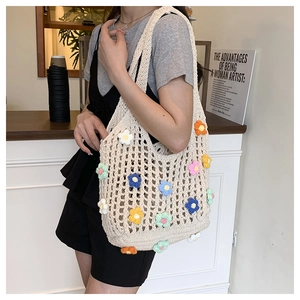 Detail of beige hollow crochet tote bag with colorful 3D floral decorations on a shoulder strap