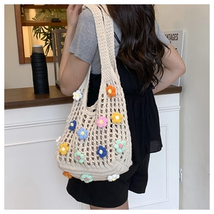 Close-up of beige crochet tote bag with colorful 3D knitted flowers on a model