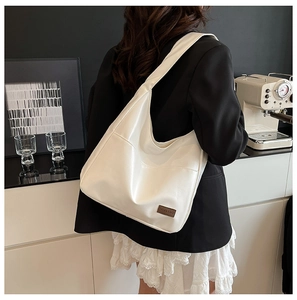 Close-up of white soft PU leather tote bag featuring a vintage brown leather label detail