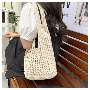Dettaglio di una borsa tote beige all'uncinetto con motivo a rombi e trama morbida