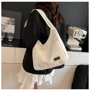 Detail of the white hobo bag showing the square logo patch and premium nylon texture