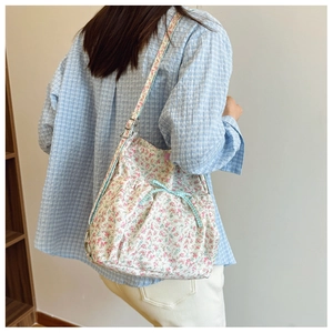 Close-up of floral canvas backpack featuring a light blue checkered bow and metal buckle