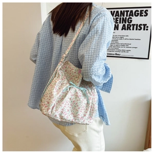 Detail view of floral canvas backpack with blue checkered drawstring and bow on a model