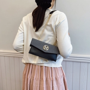 Elegante borsa a tracolla nera con logo M dorato e catena indossata da una modella