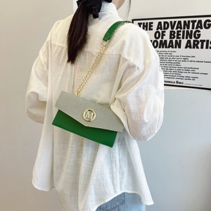 Borsa a busta in pelle verde e tessuto grigio con catena dorata indossata dal modello