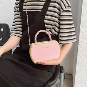 Pink crossbody box bag with gold metal frame and braided handle worn by model