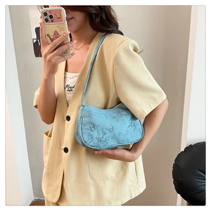Detail of light blue underarm bag featuring navy bamboo leaf print and fabric strap
