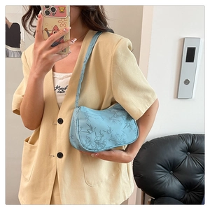 Close-up of light blue underarm bag featuring navy bamboo patterns and sleek crescent design