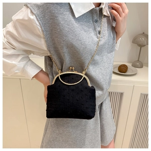 Détail du sac à bandoulière en velours noir à pois avec chaîne dorée sur un mannequin
