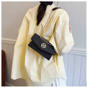 Detailed side view of women's black crossbody bag with gold M buckle and chain strap