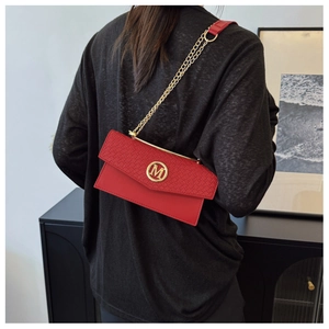 Rear view of a model wearing a red woven texture envelope bag with gold M-logo and chain