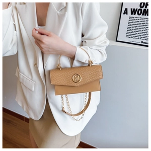 Detailed view of khaki woven flap bag with gold M logo and metallic handle