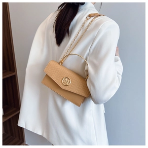 Detail showing woven texture flap, golden 'M' logo, and metal ring handle on beige bag