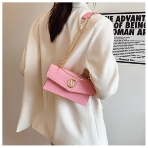 Detail of pink woven leather bag with gold M logo and chain strap on white blazer