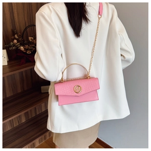 Detail of pink leather handbag featuring woven flap, gold M buckle and round metal handle
